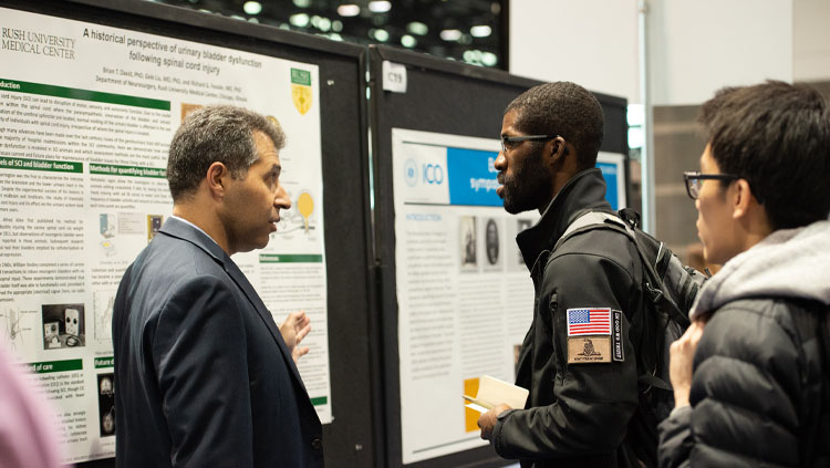 Three people discuss a poster at neuroscience 2019.